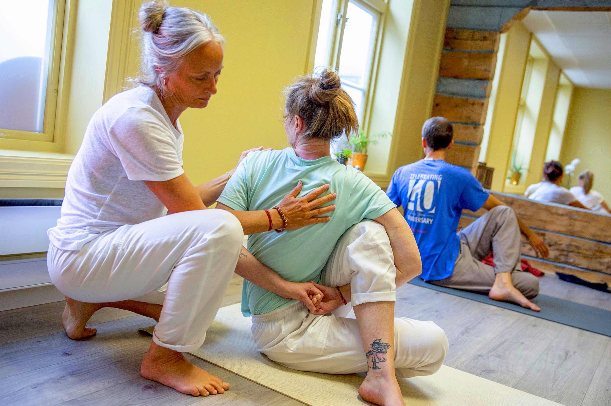 Nina Nesheim justerer en elev i en sittende vridning i yogasalen