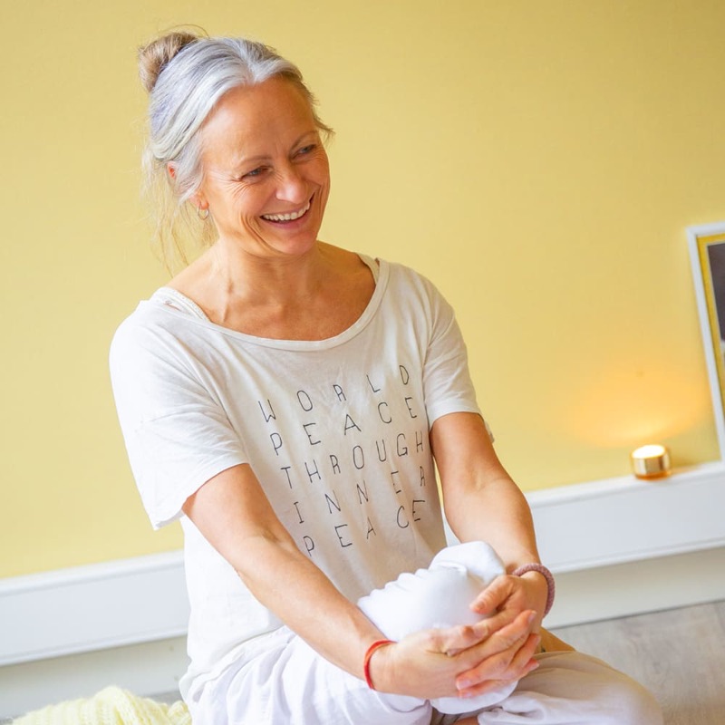 Nina Nesheim sitter på en yogamatte og smiler